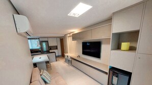 A modern kitchen with a built-in oven, a dining area with a sofa and chairs, and a TV mounted on the wall. - Beach Class Residence Eco Life (Ipojuca)