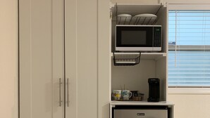 Una cocina compacta con un refrigerador blanco de dos puertas, un microondas y una cafetera sobre una encimera pequeña.