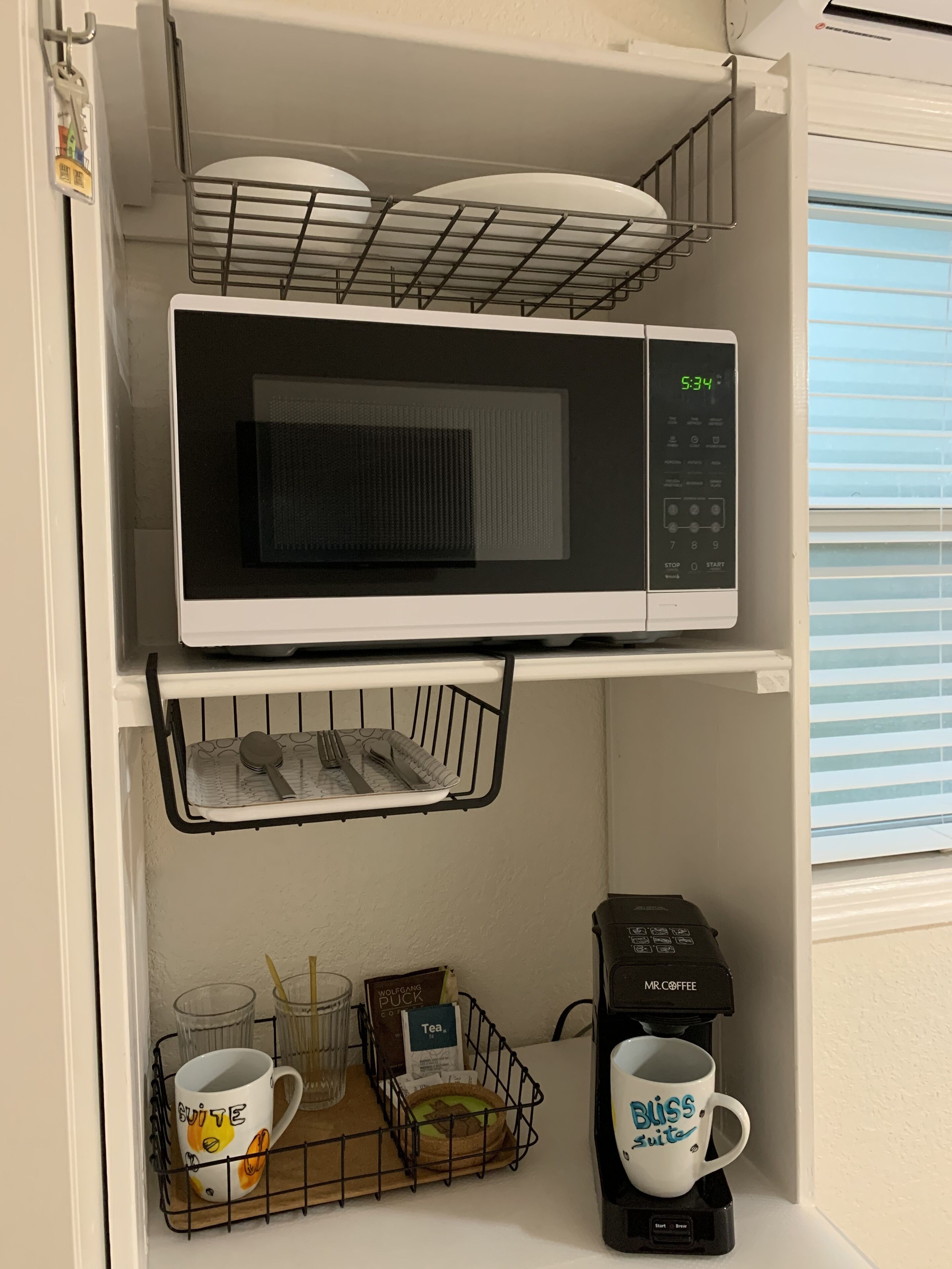 Una cocina equipada con microondas, cafetera y escurreplatos.