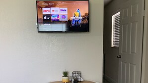 Televisor de pantalla plana montado en la pared que muestra diversos servicios de streaming.