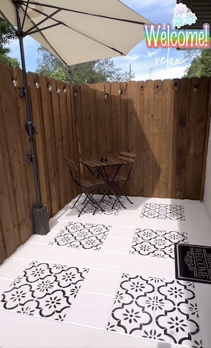 Un patio con cerramiento de madera, una mesa con sillas y baldosas con diseño.