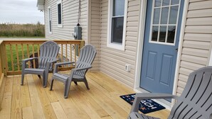 A wooden deck with three Adirondack chairs and a blue door. - Minutes to DE TURF FIELDS.  Quiet beach community.   (Frederica)