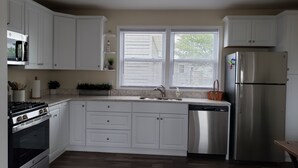 A modern kitchen with white cabinets, a stainless steel refrigerator, a dishwasher, and a gas stove. - Minutes to DE TURF FIELDS.  Quiet beach community.   (Frederica)