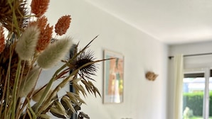 A modern living room with a wooden coffee table, a potted plant, and a painting on the wall.