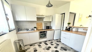 A compact kitchen with white cabinets, a microwave, a toaster, and a hexagonal patterned floor.