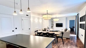 Een moderne keuken met een centraal eiland, hanglampen en een zithoek met een bank en stoelen.