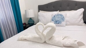 A hotel room with a bed, a nightstand with a lamp, and a decorative pillow. - recently renovated 2 Bedroom Apt, on the 2nd floor with free parking (Los Melones)