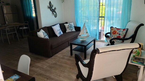 A living room with a sofa, armchair, coffee table, and a small sailboat model. - recently renovated 2 Bedroom Apt, on the 2nd floor with free parking (Los Melones)