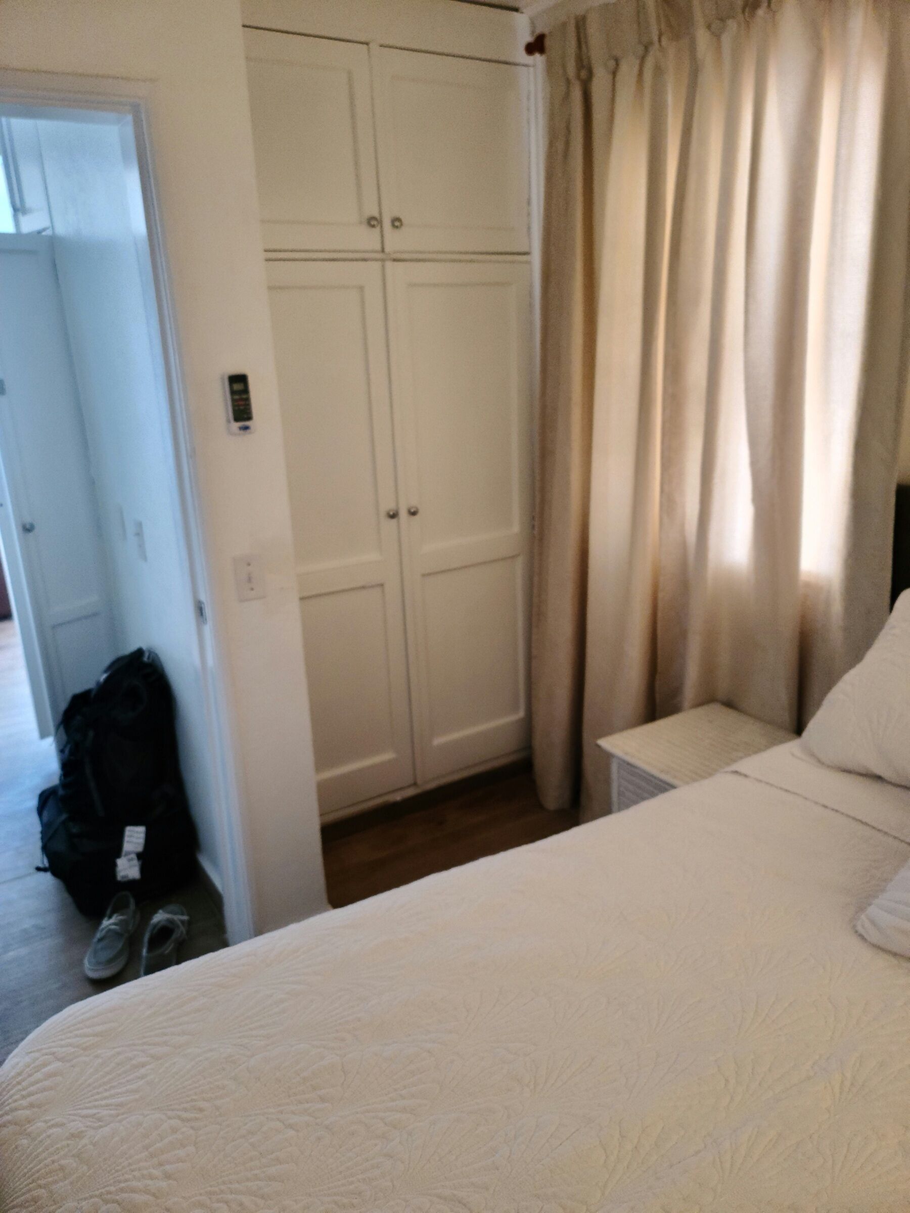 Un dormitorio con cama, mesita de noche, armario y puerta.