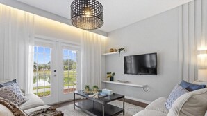 A living room with a sofa, coffee table, TV, and a door leading to a garden.