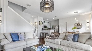A modern living room with two sofas, a coffee table, and a staircase.