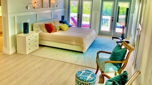 A bedroom with a bed, a nightstand, a chair, and a window. - Orchid Island Family Getaway w/Private Beach and Hot Tub (Vero Beach)