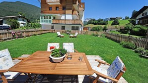 A wooden deck with a table and chairs, surrounded by a wooden fence, with a mountain in the background. - Apartments Leni 109A (Castelrotto)