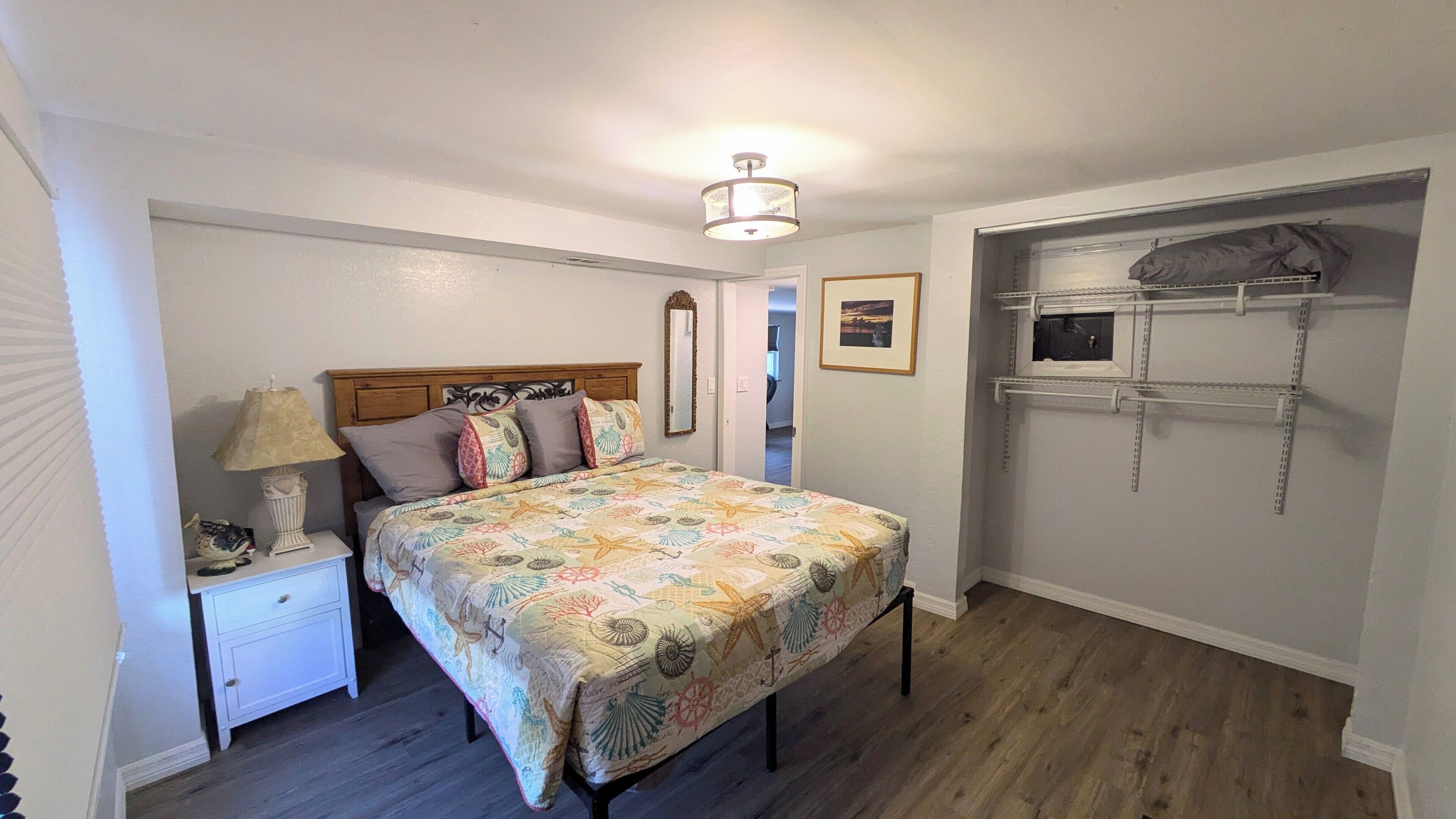 Quarto com cama, mesa de cabeceira, luminária e um closet espaçoso com prateleiras.
