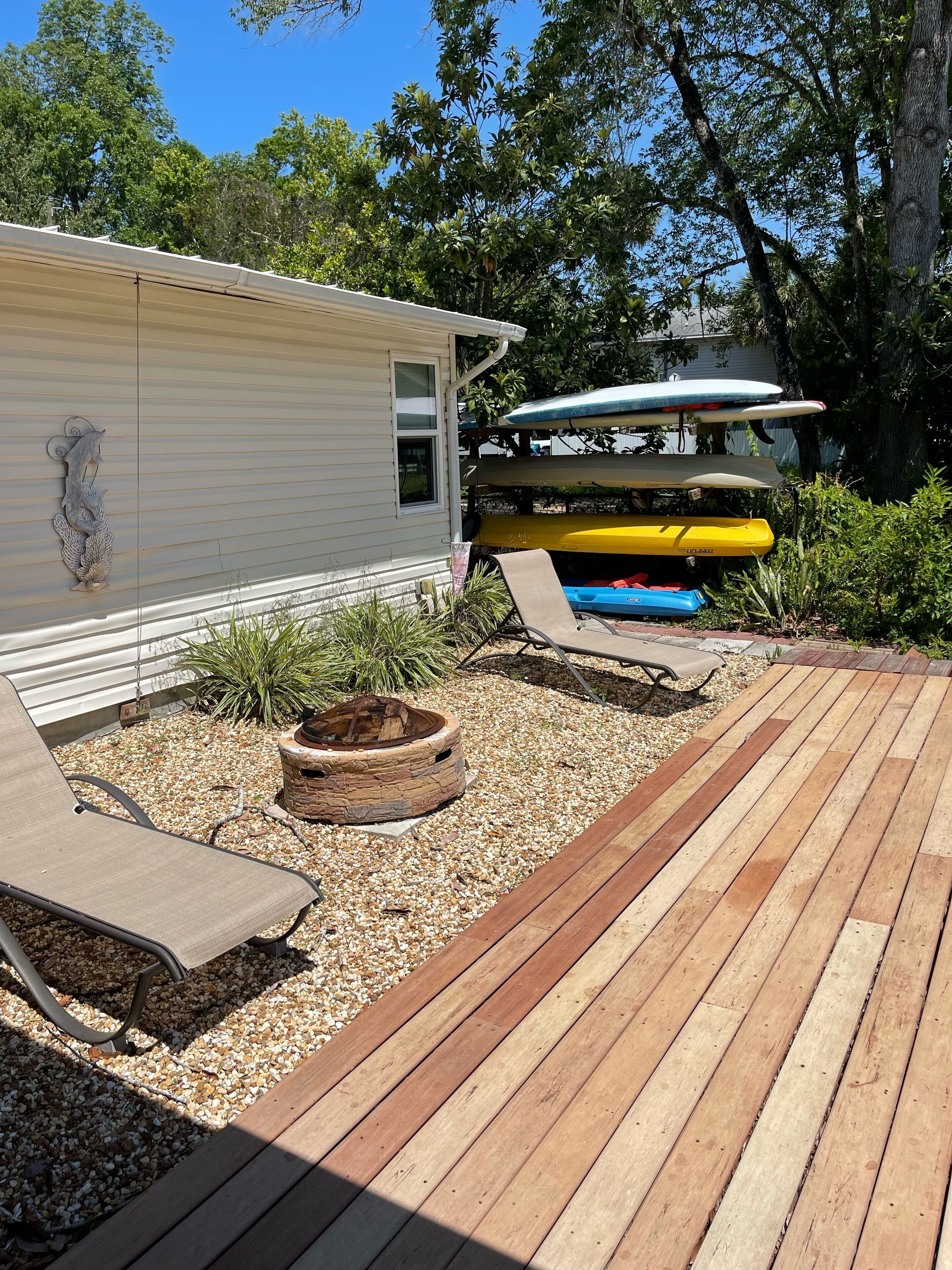 Een houten terras met vuurkorf en loungesteilen.