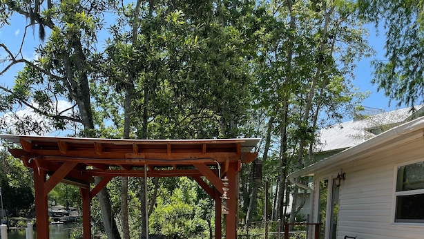 Une terrasse en bois agrémentée d’une pergola, de mobilier d’extérieur et d’un foyer.