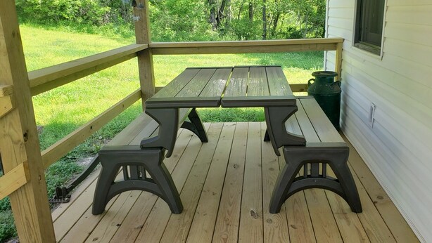Une terrasse en bois avec une table de pique-nique et des bancs.