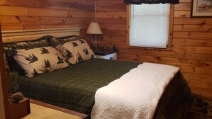 Une chambre confortable avec un lit, une table de chevet, une lampe et une fenêtre avec des stores.