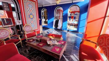 Ein luxuriöses Zimmer mit aufwendigen Möbeln, einem roten Sofa, einem roten Hocker und einem Glastisch.
