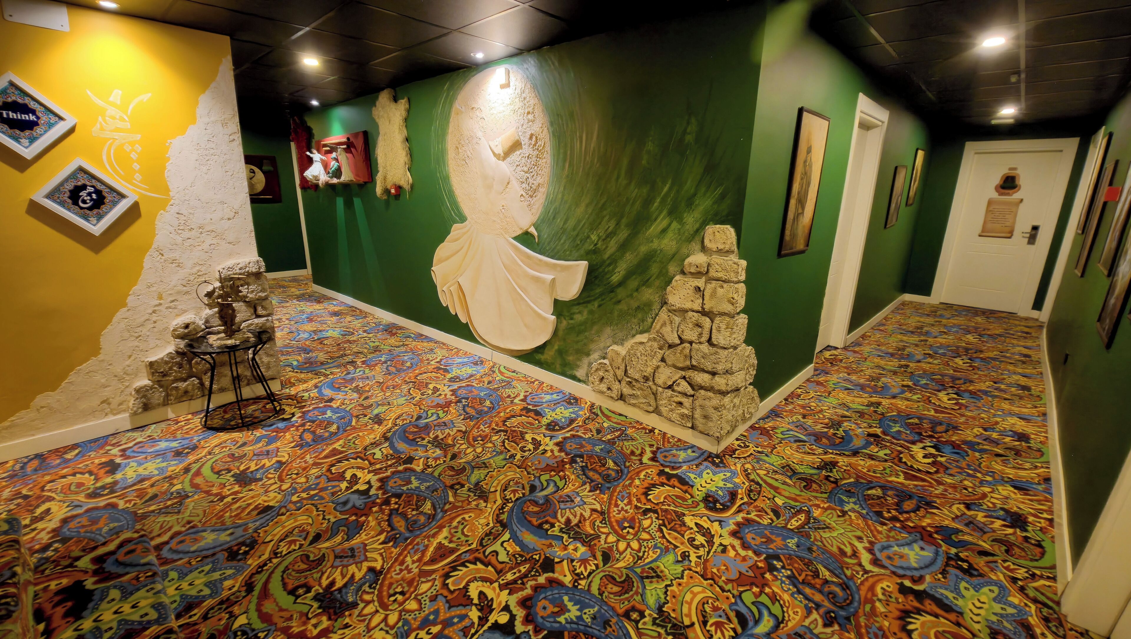 A hallway with a patterned carpet, a stone wall, and a green wall with a mural.