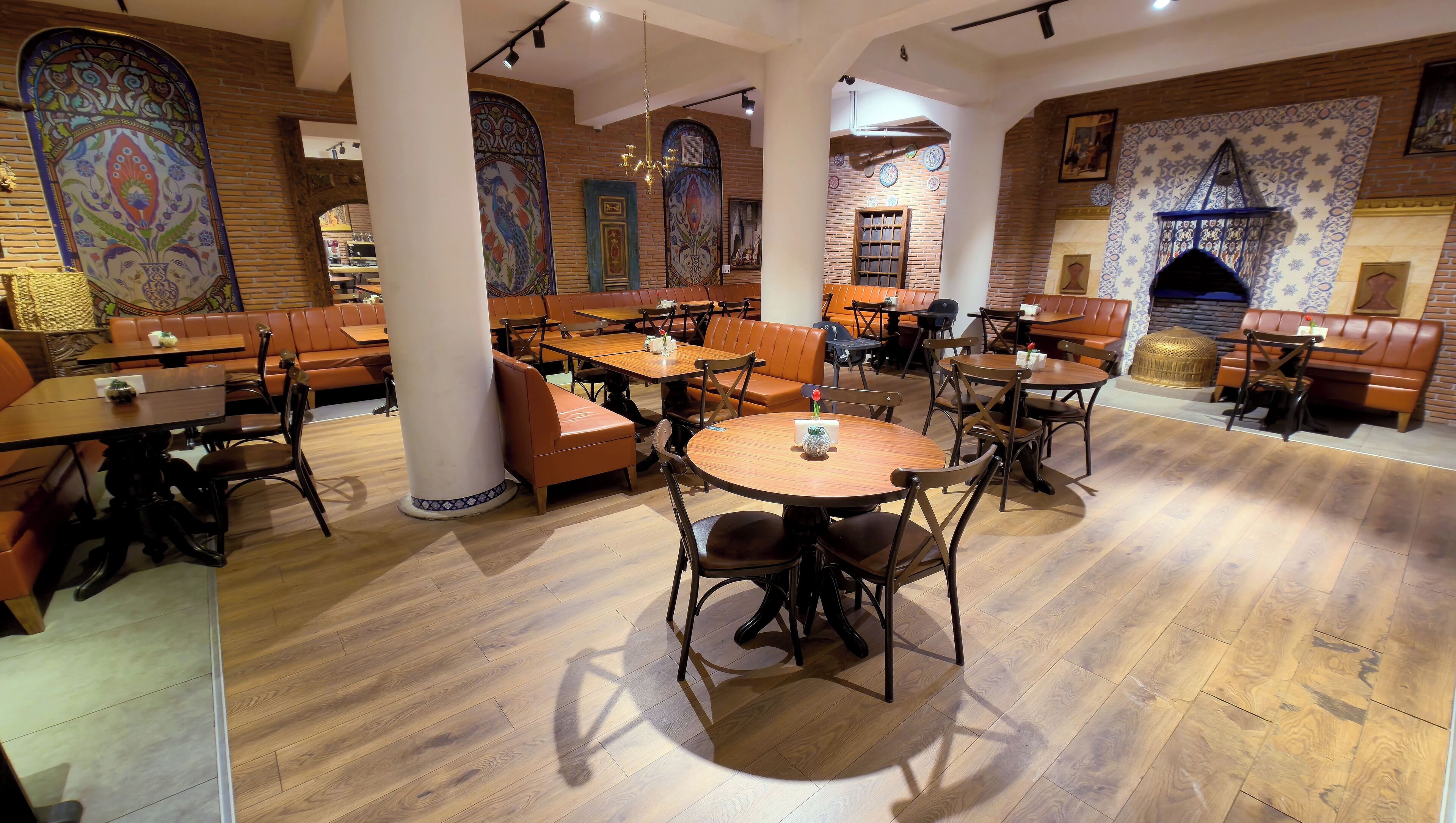 A restaurant with wooden tables and leather booths, brick walls, and decorative tiles.