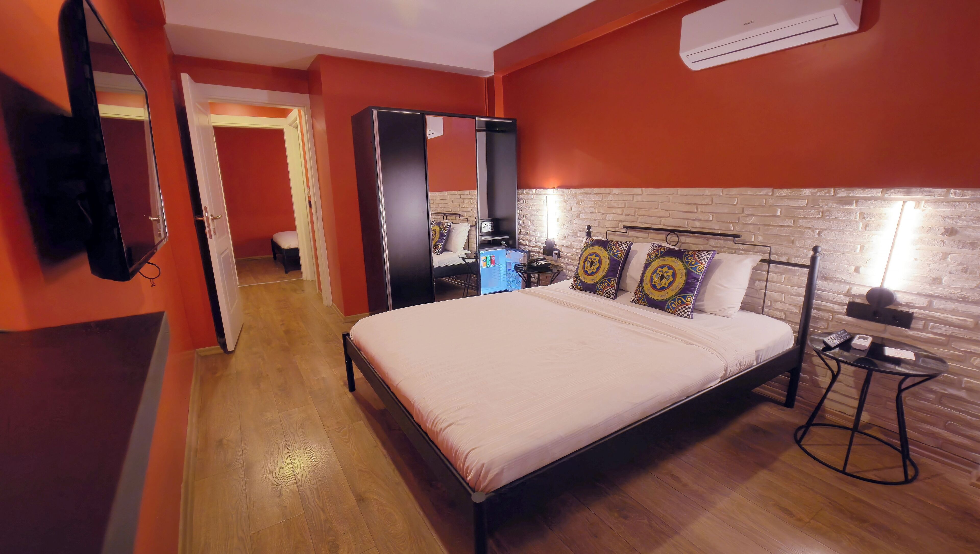 Una habitación de hotel con cama, escritorio, silla, armario y espejo.