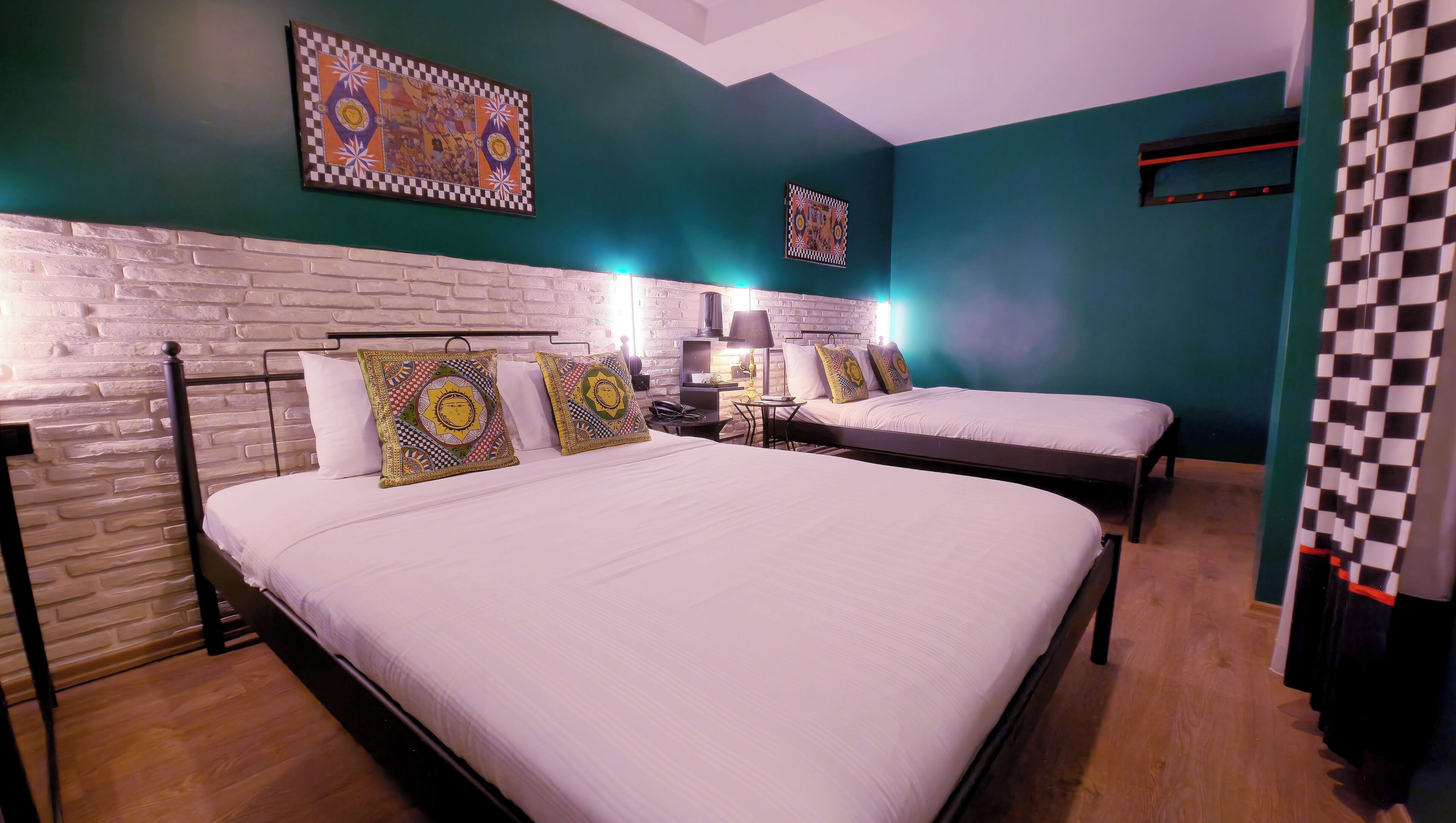 Una habitación de hotel con dos camas, una pared de ladrillo y almohadones decorativos.