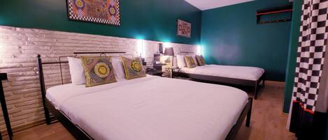 Una habitación de hotel con dos camas, una pared de ladrillo y almohadones decorativos.