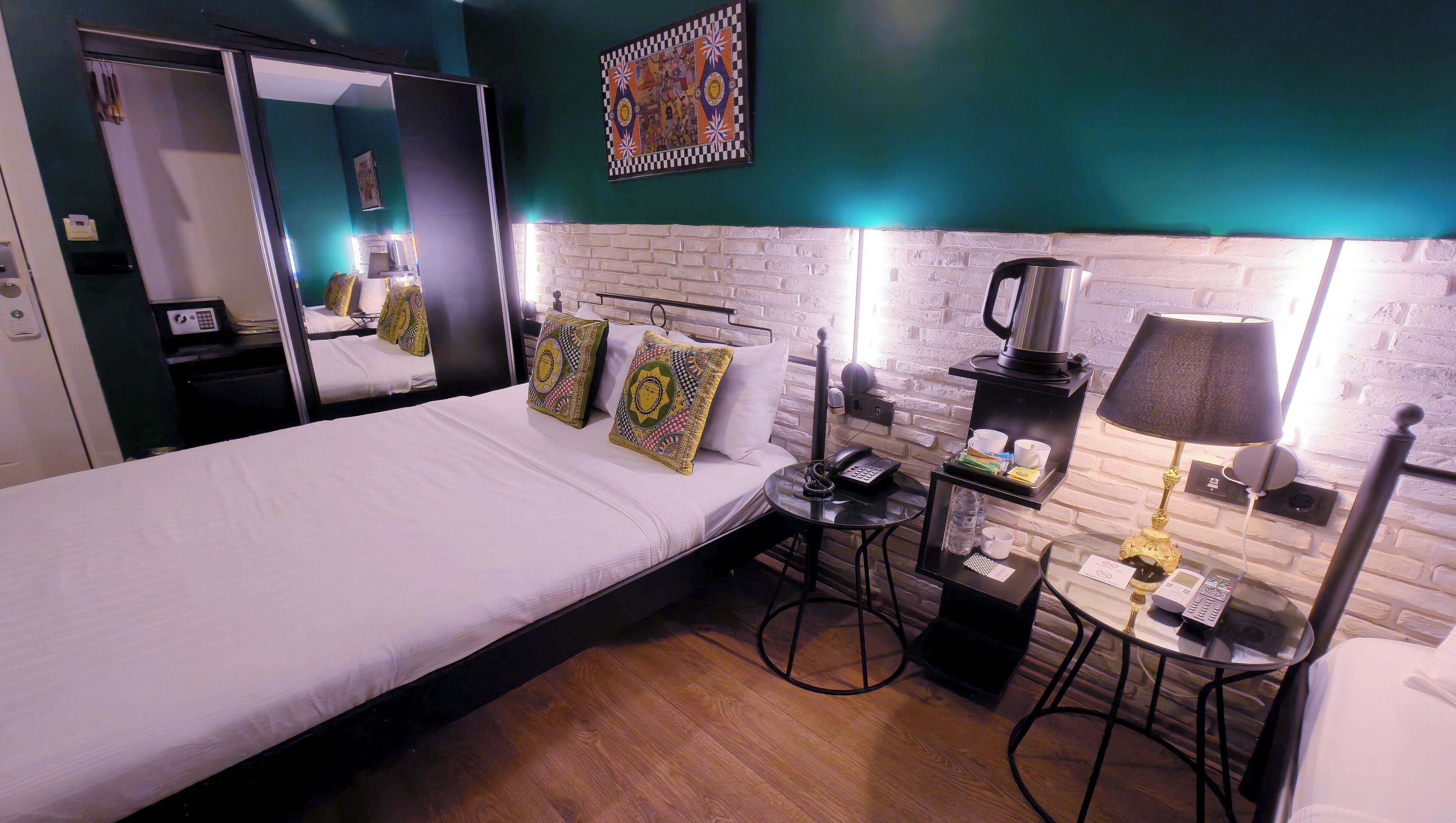 Habitación de hotel con una cama, un escritorio con cafetera, teléfono y lámpara.
