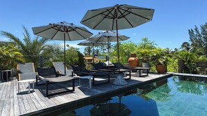 A poolside area with lounge chairs and umbrellas, surrounded by lush greenery. - Makena Hotel (Amontada)