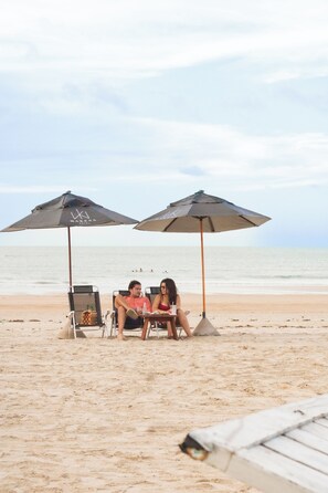 Una playa cerca, arena blanca, sillas reclinables de playa, sombrillas