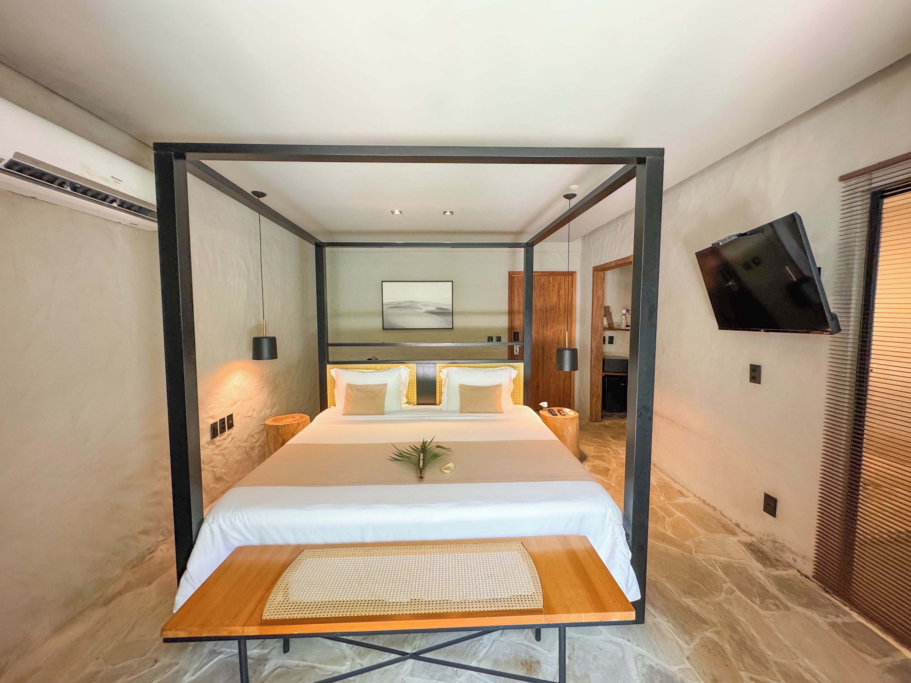 A modern hotel room with a bed, a TV mounted on the wall, and a wooden side table.