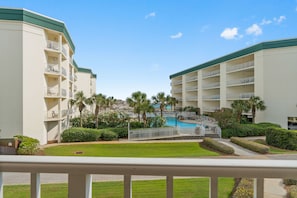 A hotel with multiple floors, a swimming pool, and palm trees. - Stunning Condo on The Beach - (Santa Rosa Beach)