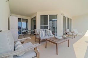 An outdoor seating area with a sofa, chairs, and a table. - Stunning Condo on The Beach - (Santa Rosa Beach)