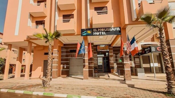 A multi-story hotel with balconies, a prominent sign reading "EL MOUSSAFIR HOTEL," and flags of various countries. - EL MOUSSAFIR HOTEL (Marrakech)
