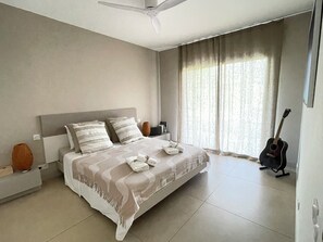 A bedroom with a bed, a ceiling fan, a guitar, and a window with curtains. - Architect-designed villa at the foot of the Albères Mountains, 7 km from the beaches (Sorède)