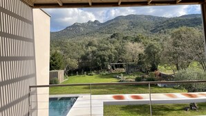 Vista de uma área externa coberta com piscina, com paisagem montanhosa ao fundo.
