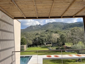 Vue depuis un espace extérieur abrité, avec une piscine, donnant sur un paysage montagneux.