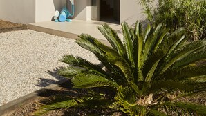 Uma casa moderna com telhado plano e cobertura de ripas de madeira sobre a entrada, além de uma pequena janela lateral.