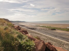 A coastal walkway with a rocky path, a wooden fence, and a bench.