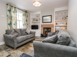 A living room with a fireplace, grey sofas, and a television.