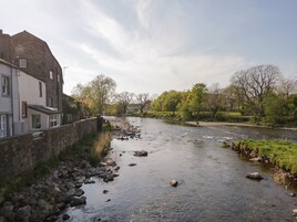 A river with a stone wall on one side and a building with multiple windows on the other.
