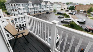 Un balcon donnant sur un parking et des immeubles d’habitation.