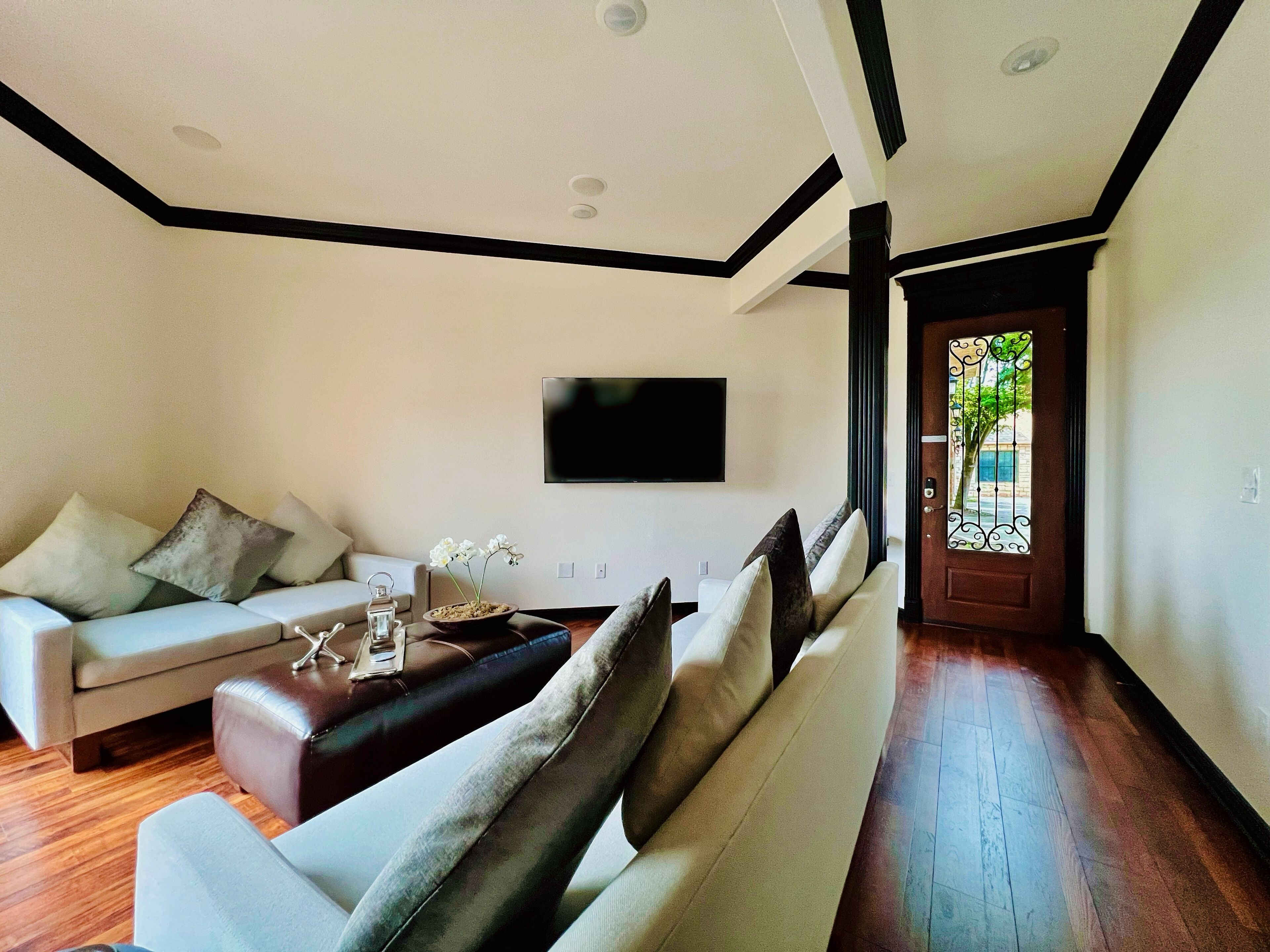 Ein modernes Wohnzimmer mit einer Couch, einem Couchtisch und einem an der Wand montierten Fernseher.