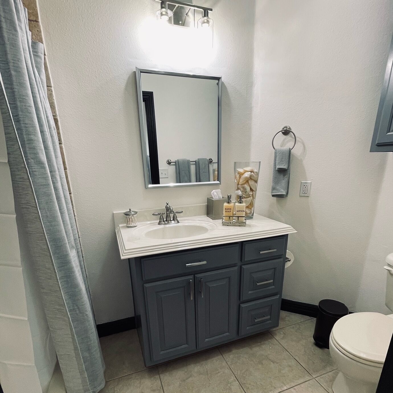 Ein Badezimmer mit zwei Waschbecken, einem Spiegel, einem Handtuchhalter und einer Toilette.