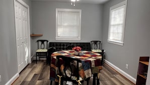 Un coin repas avec une table ronde, des chaises, une nappe matelassée et un ventilateur de plafond.