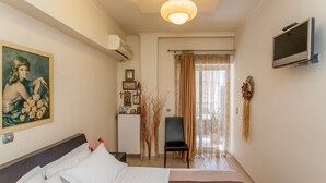 Una habitación de hotel con cama, escritorio, silla, televisor y un cuadro en la pared.