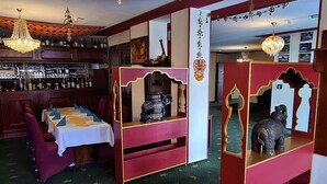 Ein Restaurant mit Barbereich, roter und goldener Dekoration und einem Chandelier.