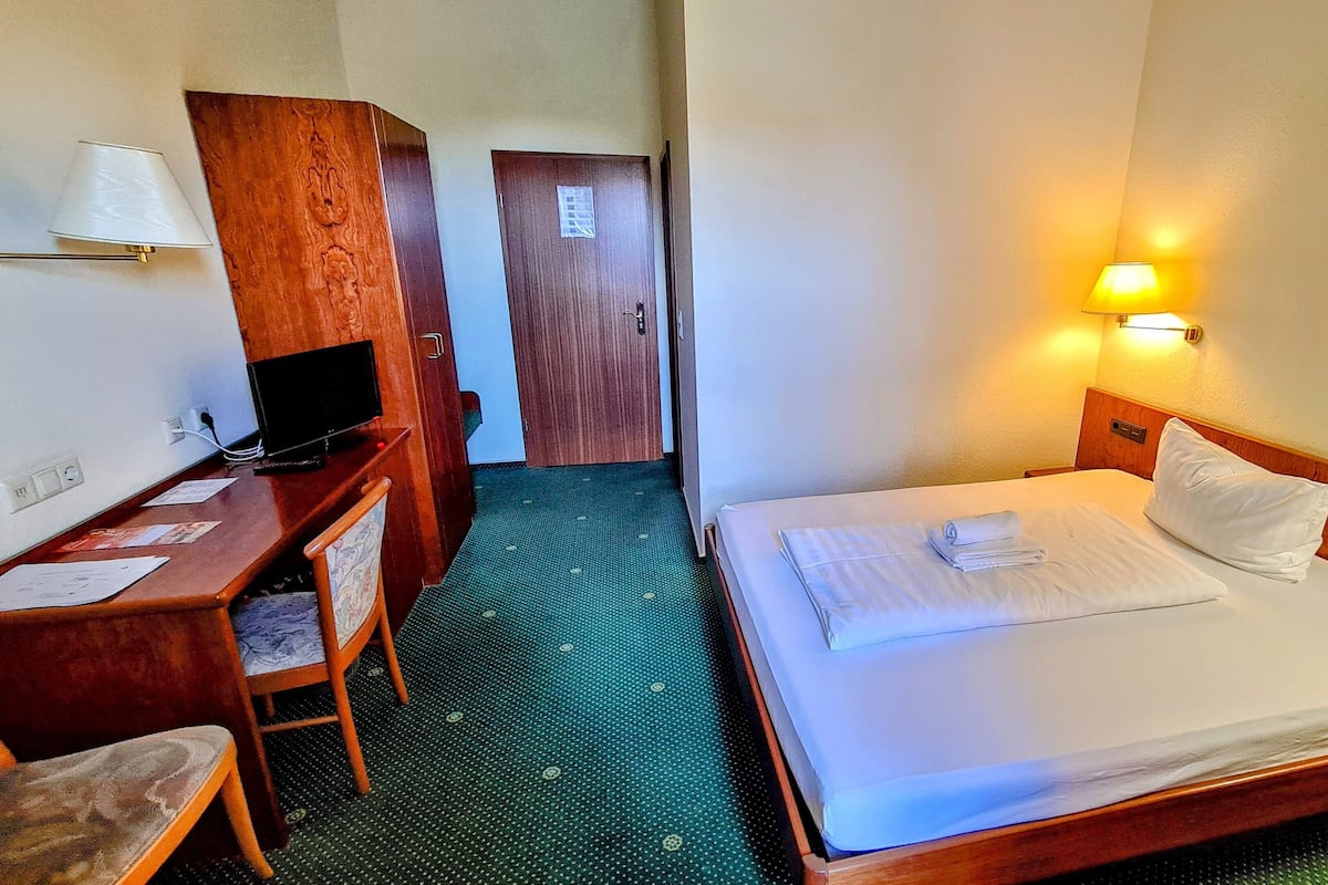 Une chambre d’hôtel comprenant un lit, un bureau avec une télévision, une chaise et une porte donnant sur une autre pièce.