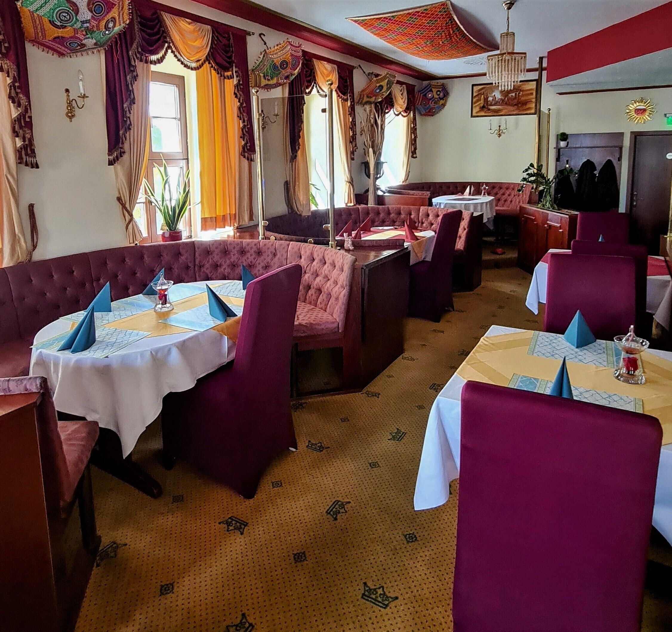 Ein Restaurant mit Sitzboxen und Tischen, einige davon mit blauen Servietten.